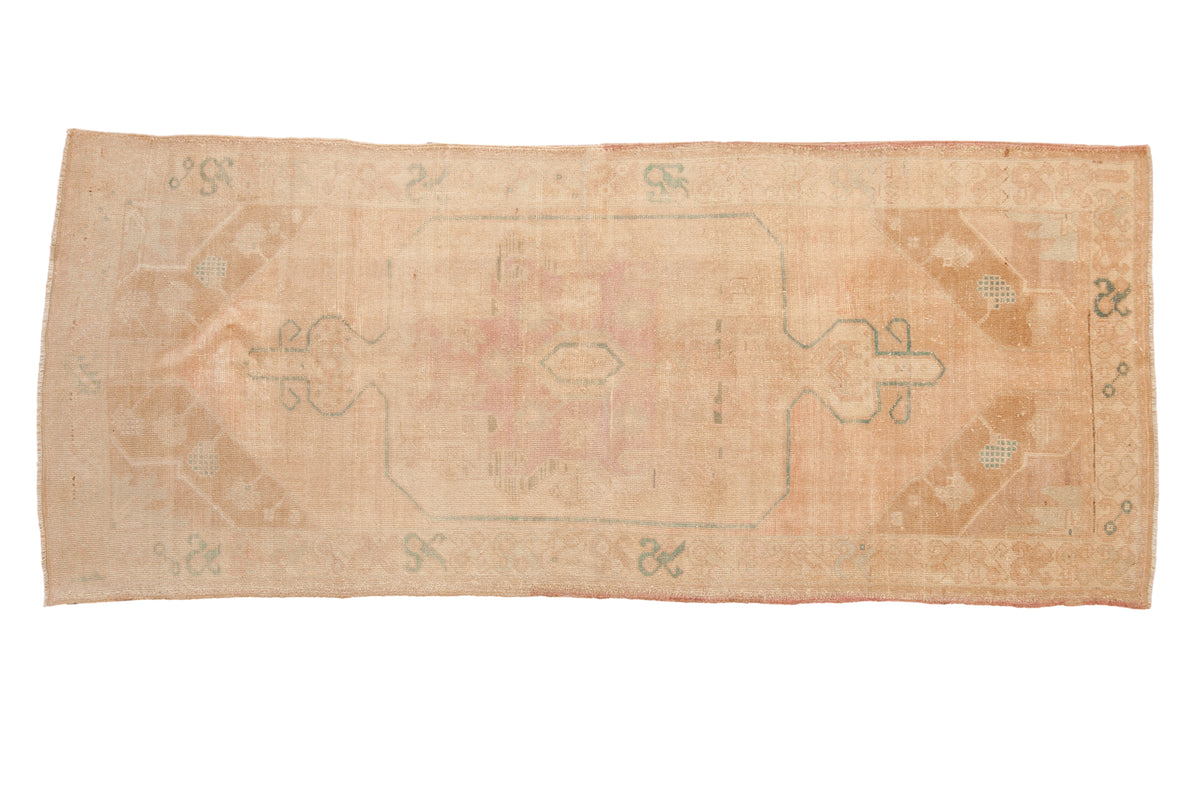 Vintage distressed Oushak rug runner with a large central medallion in soft tones of ivory, pink, and pale turquoise.