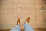 Close view of a distressed Oushak rug's low pile with soft, faded pink and turquoise patterns.