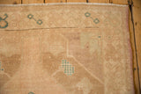 Corner detail of a distressed Oushak rug showing low pile and turquoise motifs.