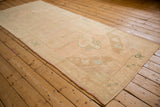 Angled view of a distressed Oushak runner, highlighting its full length and soft, faded palette.