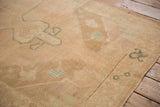 Detail of the distressed weave and pale turquoise grape cluster motif on a vintage Oushak rug corner.