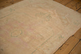 Low pile of a distressed vintage Oushak rug showing even wear with pale pink and sea foam accents.