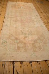A low-angle view showing the length and low-pile, worn texture of the vintage Oushak runner.