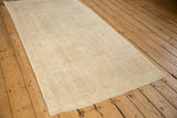 Angled view of a distressed Oushak runner highlighting its even wear and soft, muted color palette.
