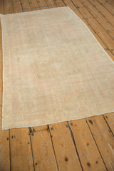 Angled view of a distressed Oushak runner highlighting its low, even pile and pale dusty rose field.