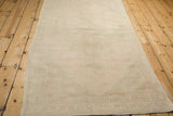 Angled view from the end of a vintage Oushak runner, showing its light-washed, sandy-beige texture.