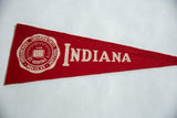 Cream 'Indiana' text on a vintage red felt pennant, showcasing aged texture.