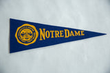 Close-up of vintage Notre Dame felt flag's yellow crest and text.