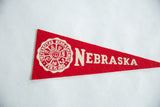 Vintage red felt Nebraska pennant featuring white university crest and 
