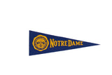 Blue vintage Notre Dame felt pennant with yellow school crest and lettering.