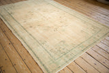 Distressed ivory Oushak carpet corner with faded mint green border and vinery pattern.