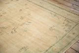 Distressed Oushak carpet showcasing its low pile and faded ivory and mint green vinery.
