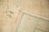 Distressed vintage Oushak rug corner, revealing striped foundation and pink selvage.