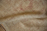 Close-up of the distressed rug's hand-knotted pile showing wear to the foundation.
