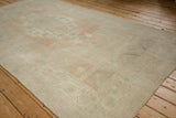 Distressed vintage Oushak rug with even wear, featuring faded pale pink, seafoam, and ivory tones.