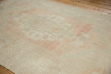Distressed Oushak carpet showing an abrashed field with muted pale pink and sea foam tones.