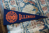 The orange 1867 crest on the vintage University of Illinois navy felt pennant.
