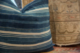 Textured indigo African textile pillow, varied blue and off-white stripes with visible stitching.