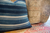 Vintage indigo African textile pillow with varied blue shades and white stripes.