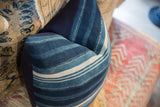 Varying indigo blue and white stitched stripes on a textured African textile pillow.
