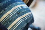 Vintage African textile pillow with varied indigo stripes and visible panel stitching.