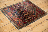 Angled profile of a vintage Farahan Sarouk rug highlighting the charcoal Herati medallion and cranberry red spandrels.