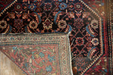 Vintage Farahan Sarouk rug corner folded to show the hand-knotted foundation and side cord.