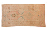 Distressed vintage Oushak rug runner with floral medallions in soft blush pink, aqua, and beige.