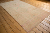Angled view showcasing the even wear and faded floral pattern of a vintage Oushak runner.