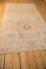 Angled view down the length of the distressed Oushak runner with its soft pink and aqua palette.