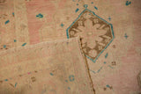 A vintage Oushak rug's corner folded to show the handwoven back and side selvage detail.