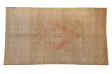 Vintage distressed Oushak carpet with a dusty blush stepped medallion on a neutral sand and ivory field.