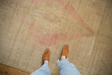 Low-pile texture and even wear of a distressed Oushak carpet in pale gold and dusty rose tones.