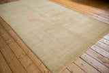 Angled view of a vintage Oushak carpet showing its distressed, low-pile texture and pale gold color.