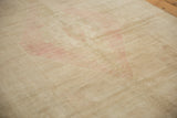 The low, evenly worn pile of a distressed Oushak rug in sand and dusty blush tones.