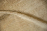 Folded close-up showing the even, low pile texture of the distressed sandy Oushak carpet.