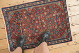 Overhead view of a vintage Malayer rug, showing the scale of its brick red and blue Herati motif.