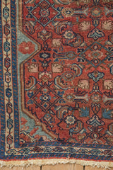 Corner detail of a fine Malayer rug showing low-pile wear on its gem-tone blue and red Herati motif.