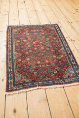 Angled view of a traditional Persian Malayer rug with intricate red and blue Herati motifs.