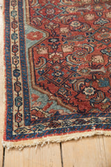 Angled view of the boteh border and worn knot heads on a vintage Persian Malayer mat.