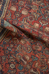 A folded vintage Malayer rug showing the even wear across its hand-knotted pile.
