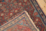 Folded corner of a vintage Malayer rug showing the low-pile texture and woven foundation.