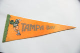 Green border, football player graphic, and time-softened orange felt on the vintage Tampa Bay pennant.