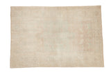 Vintage distressed Oushak rug with a faint pattern in soft ivory, pale green, and mauve tones.