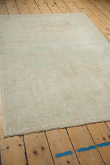 Angled view of the distressed rug's corner, showing even wear and intact selvage.