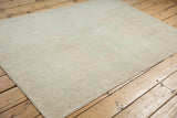 Angled view of a distressed Oushak rug showing its faded pattern and even-worn texture.