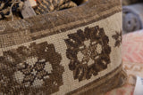 Close-up of hand-knotted pile on vintage Turkish rug pillow. Brown and beige geometric pattern.