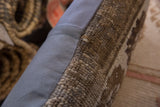 Side view of the vintage rug fragment pillow, contrasting its knotted pile with blue-gray fabric.