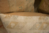 Close-up of vintage Turkish rug fragment pillow's hand-knotted edge, soft beige, and faded blue-green.