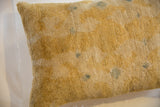Textured antique Chinese rug fragment pillow in aged tan with muted blue motifs.